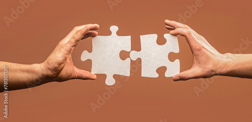 Hand connecting jigsaw puzzle. Man hands connecting couple puzzle piece. Closeup hands of man connecting jigsaw puzzle. Two hands trying to connect couple puzzle photo