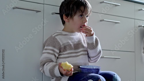 Kickstarting The Day Right - Youngster Enjoys A Fruit Variety For Breakfast While Perched On A Kitchen Seat photo