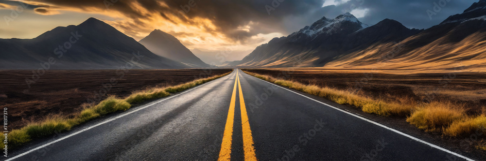 An empty road leading towards distant mountains with distinct yellow lane markings, emphasizing the asphalt texture.