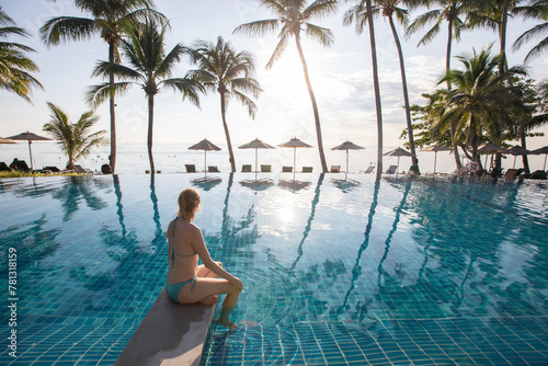 woman in swimsuit sitting near beautiful swimming pool of luxury beach hotel resort © Song_about_summer