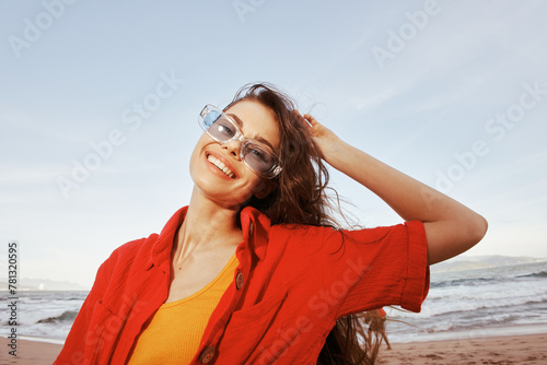 Smiling Woman Embracing Freedom: A Colorful Portrait of a Trendy Model at the Beach with a Wide Angle View, Enjoying the Sunset by the Ocean in Summer