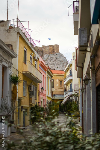 Charming Athens street with view of Parthenon, Greek flag waving proudly under the blue sky.