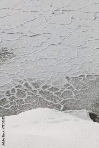 Frozen sea ice covered with snow at seashore in winter.