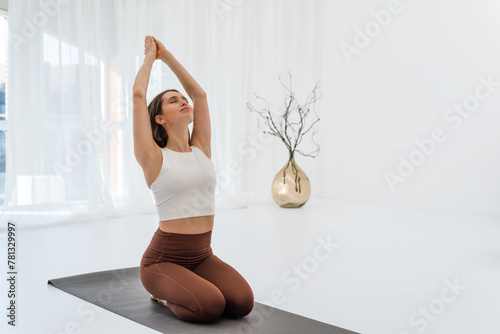 Young woman doing morning exercise on mat during yoga practice. Sport workout. Concept of healthy lifestyle, female wellness.