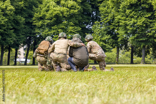 Soldiers and a civilian are waiting to be picked up by a helicopter