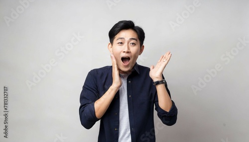 Portrait of a young asian man shouting on grey background.