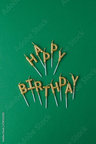 Canvas Print golden cake candles in the shape of happy birthday letters lie on a green backgr