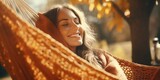 A woman is relaxing in a hammock, smiling and enjoying the moment. Concept of peace and contentment, as the woman takes a break from her daily routine to unwind and appreciate the beauty of nature