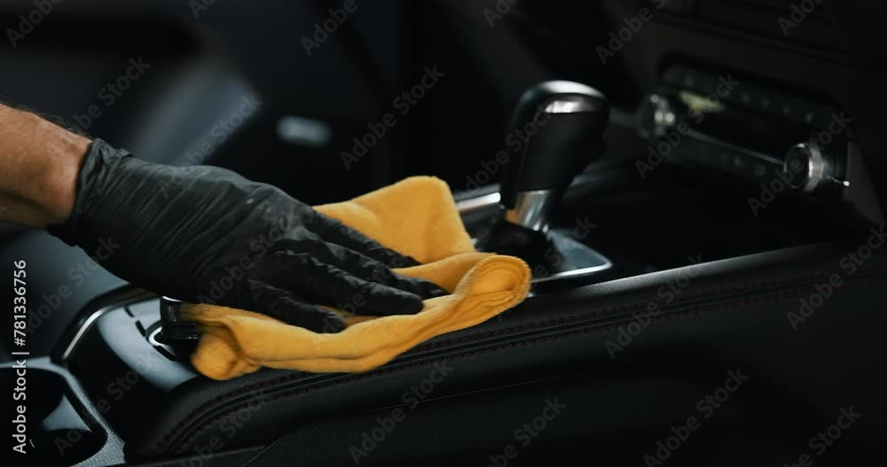 car interior cleaning. hand with microfiber cloth cleans center console