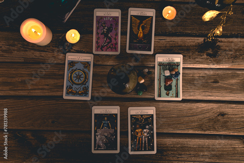 Tarot cards including The Fool and The Lovers alongside crystals and candles on a textured wooden table. © Juan