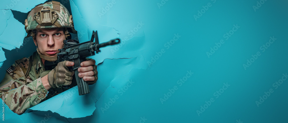 Fototapeta premium An armed soldier in combat gear peers through a blue paper tear, symbolizing alertness and readiness