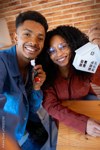 Vertical shot couple showing a mini wooden house and a key with a key ring