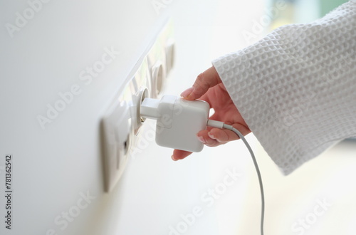 Obraz na płótnie Woman hand in robe gown inserts white charger into socket in hotel rooms or at home. Charge gadgets correctly concept w salonie