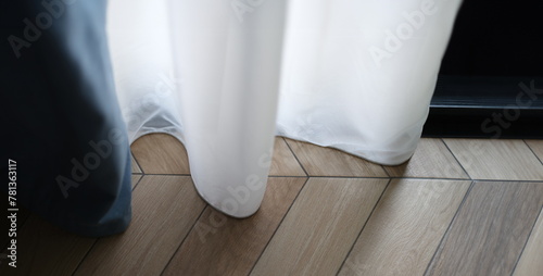 Beautiful white curtains indoors and wooden parquet floor closeup. Curtain design and floor concept