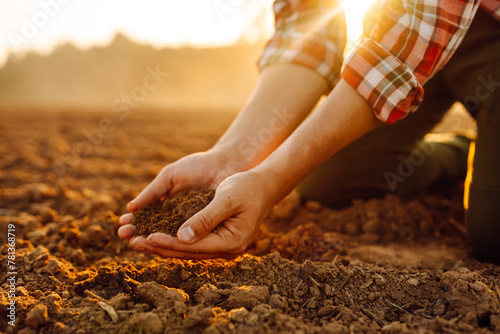 Farmer's hands holding soil, checking soil health before sowing. Ecology, agriculture concept. © maxbelchenko