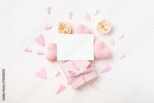 Festive background for Birthday, Woman or Mothers Day. Empty paper card, hearts, rose flowers and gift box on white table top view.