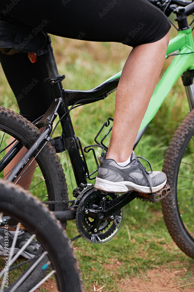 Fototapeta premium Person, legs and cyclist with bicycle in nature for paddling, cycling or outdoors sports in health and wellness. Closeup of biker, foot or shoes on mountain bike for off road travel, ride or fitness