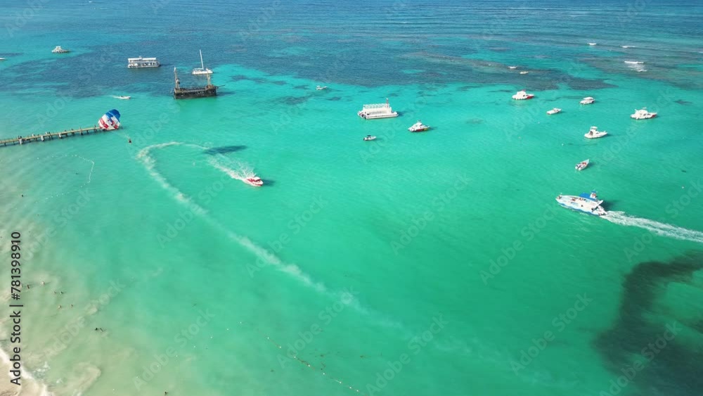 Aerial scenic view of Caribbean Sea featuring boats, parasailing, and water-based recreational activities for tourists, set against backdrop of turquoise waters. Dominican Republic, Punta Cana Aerial scenic view of Caribbean Sea featuring boats, parasailing, and water-based recreational activities for tourists, set against backdrop of turquoise waters. Dominican Republic, Punta Cana