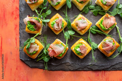 Puff pastry bites with Parma ham, pea puree, and pea shoots