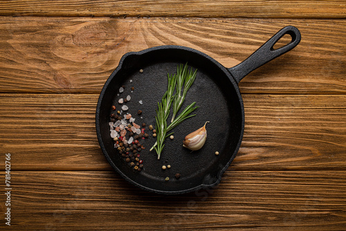 Black cast iron frying pan skillet with fresh rosemary, garlic, salt and pepper photo