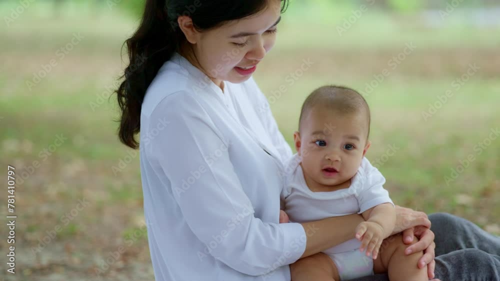 Asian mothers or single moms are smiling and hugging newborn babies. Family doing activities and relaxing in the park. Concepts about the duties of a wife and mother in raising children and family. Asian mothers or single moms are smiling and hugging newborn babies. Family doing activities and relaxing in the park. Concepts about the duties of a wife and mother in raising children and family.
