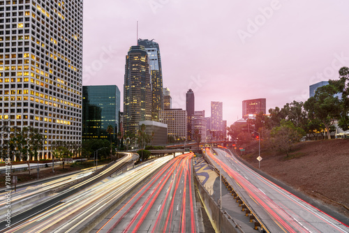 Long Exposure of a busy freeway bordering Los Angeles downtown high rise buildings at sunset in autumn. Light trails.