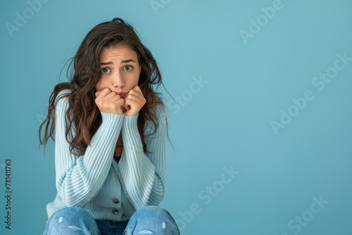 Femme anxieuse se rongeant les ongles sur un fond bleu, espace pour texte photo