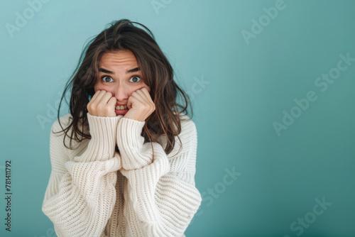 Femme anxieuse se rongeant les ongles sur un fond bleu, espace pour texte photo