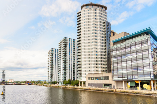 Modern residential towers by beside a glass office building in a quayside redevelopment on a partly cloudy summer day