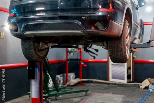 close-up At a service station black dirty car is lifted on a lift to change a wheel