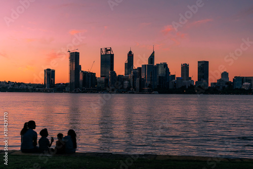Family watching the pink sunset behind the Perth city skyline