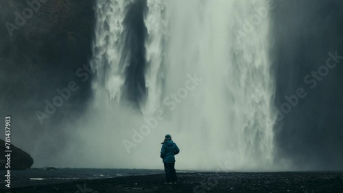 A girl stands in front of a waterfall photo
