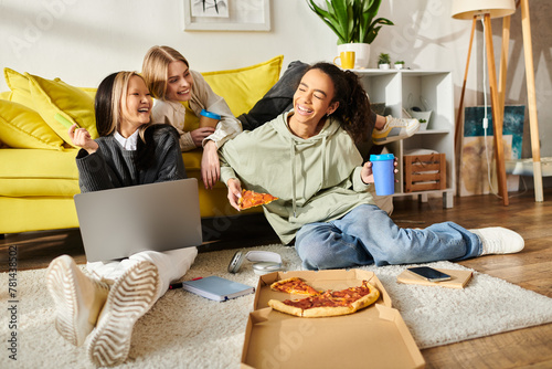 Tableau sur toile Diverse group of teenage girls sitting together on the floor, enjoying slices of pizza in a cozy home setting