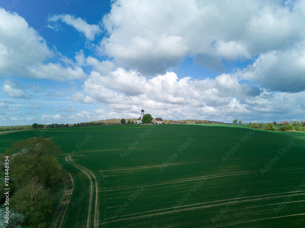 Small church with cemetery in the middle of blooming fruit trees and fields captured with a drone in spring