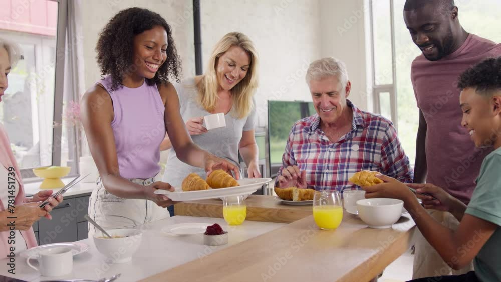 Three generation family with teenage children at home preparing and eating breakfast in kitchen at home together- shot in slow motion Three generation family with teenage children at home preparing and eating breakfast in kitchen at home together- shot in slow motion