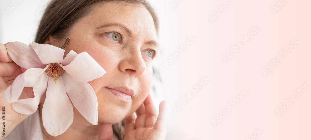 aging woman with magnolia flower looks herself in mirror, noticing wrinkles, changes in facial contour and sagging eyelids, cosmetic anti-aging procedures, natural process growing older aging woman with magnolia flower looks herself in mirror, noticing wrinkles, changes in facial contour and sagging eyelids, cosmetic anti-aging procedures, natural process growing older