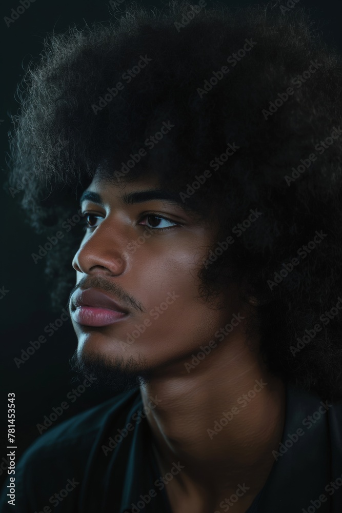 Portrait of a young man showcasing his full, curly afro hairstyle against a dark background Portrait of a young man showcasing his full, curly afro hairstyle against a dark background