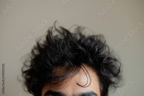 Close-up detail of a messy bedhead hairstyle of a man with unruly black hair, showcasing the natural texture and disheveled look in his morning wake-up routine photo