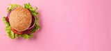 A delectable veggie burger with beetroot, lettuce, and onion, topped with sesame seeds on a vibrant pink background.