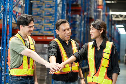 Group of Asian warehouse workers join hands together in storage warehouse. Team of male and female warehouse workers at work. Completed finish job. Successful of work concept