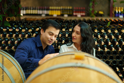 Portrait of wine testing expertises discussing together about wine in the wine cellar.