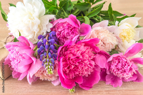 Bunch of pink, white and purpld peony flowers on a wooden background; Happy mother's day greeting card
