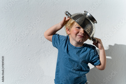 Little boy putting colander on his head . cheerful blond boy with a sieve on his head. positive kid