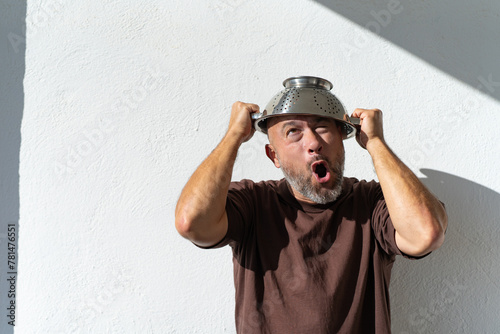 bearded cheerful man with a colander on his head. cheerful portraits of a man with a colander