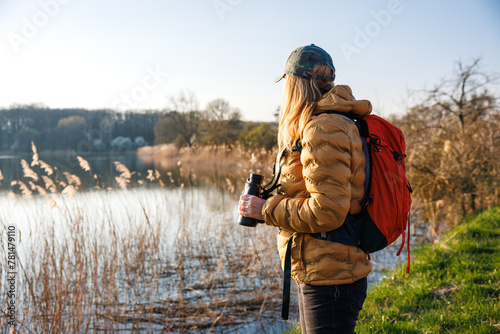 Woman biologist is watching birds with binoculars. Bird watching and observation wildlife animals at lake. Biology in nature