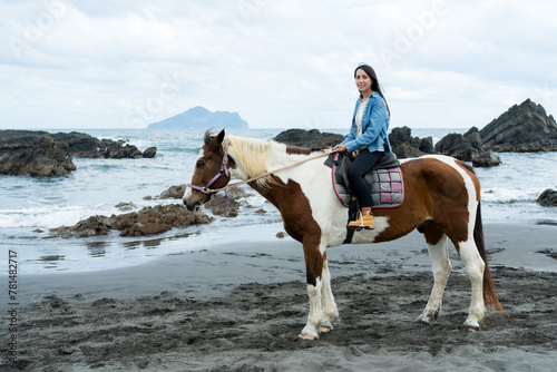 Tourist woman ride a horse beside the sea beach