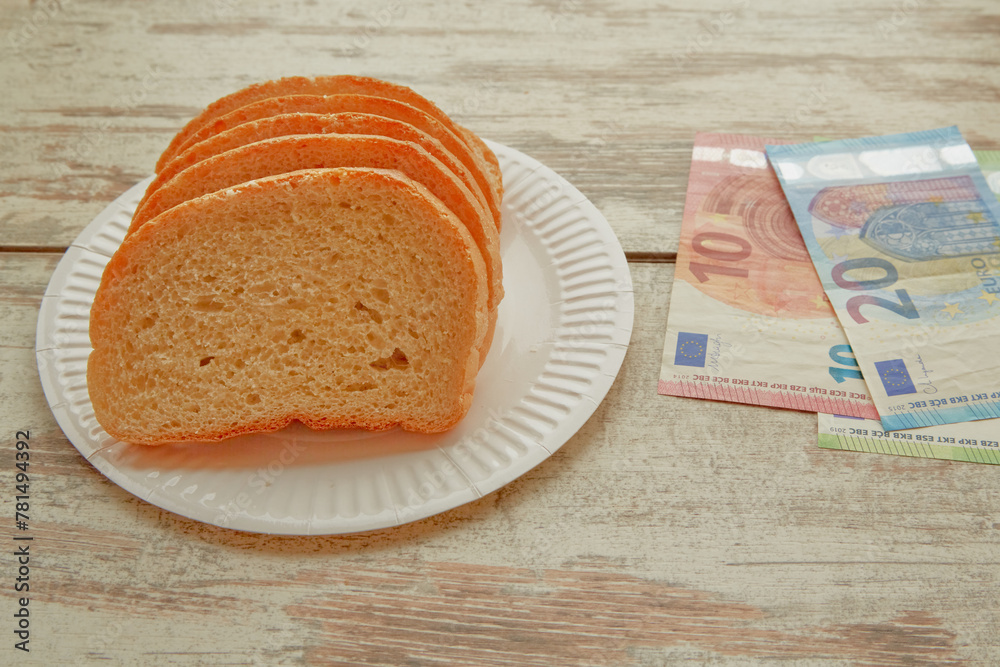 Sliced bread on a plate and euro bills nearby, rising food prices, increase in bread prices, social payments - obrazy, fototapety, plakaty 