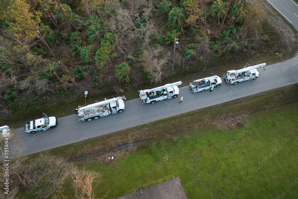 Electrical service company restoring power repairing damaged power lines after hurricane in Florida suburban area