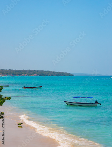 Scenic view of Playa Blanca in Baru, Cartagena, Colombia with clear turquoise waters, boats, and sandy beach under a blue sky