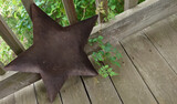 large rusty sheet metal star leaning against railing on wooden porch 